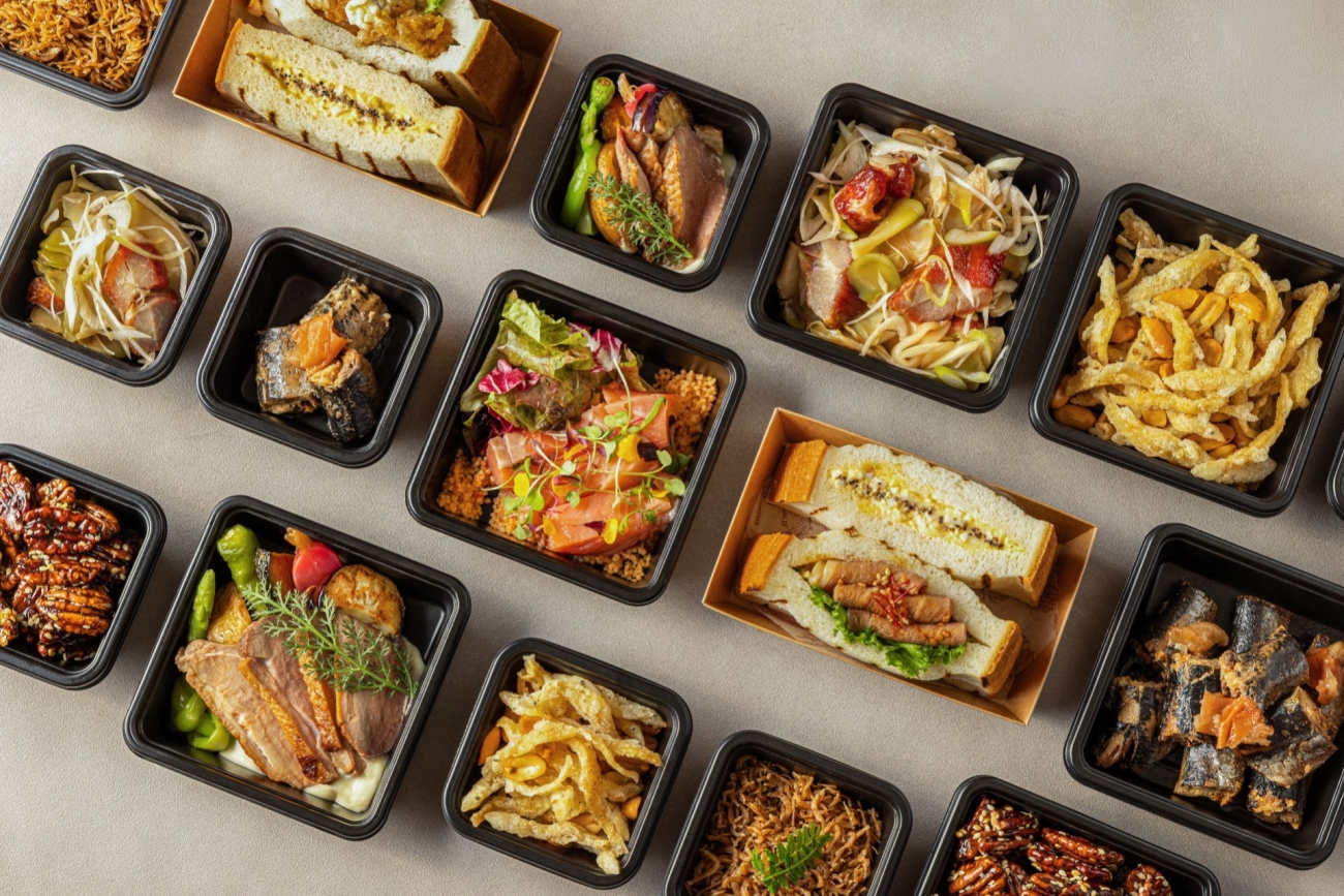 本格惣菜ブランド「Sheraton Deli（シェラトン・デリ）」の各種テイクアウトお惣菜が木目のテーブルに並ぶ集合写真